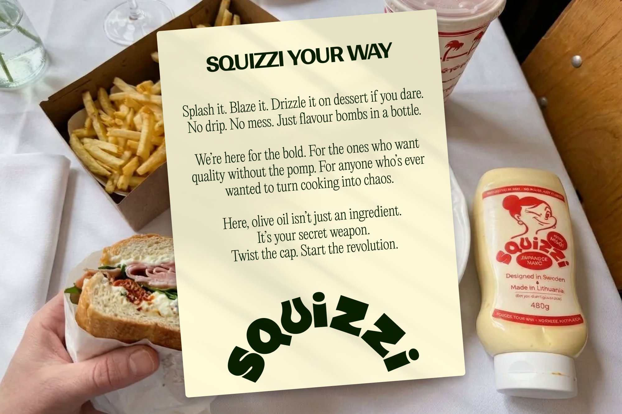 Squizzi Your Way manifesto card on a table with a sandwich and fries